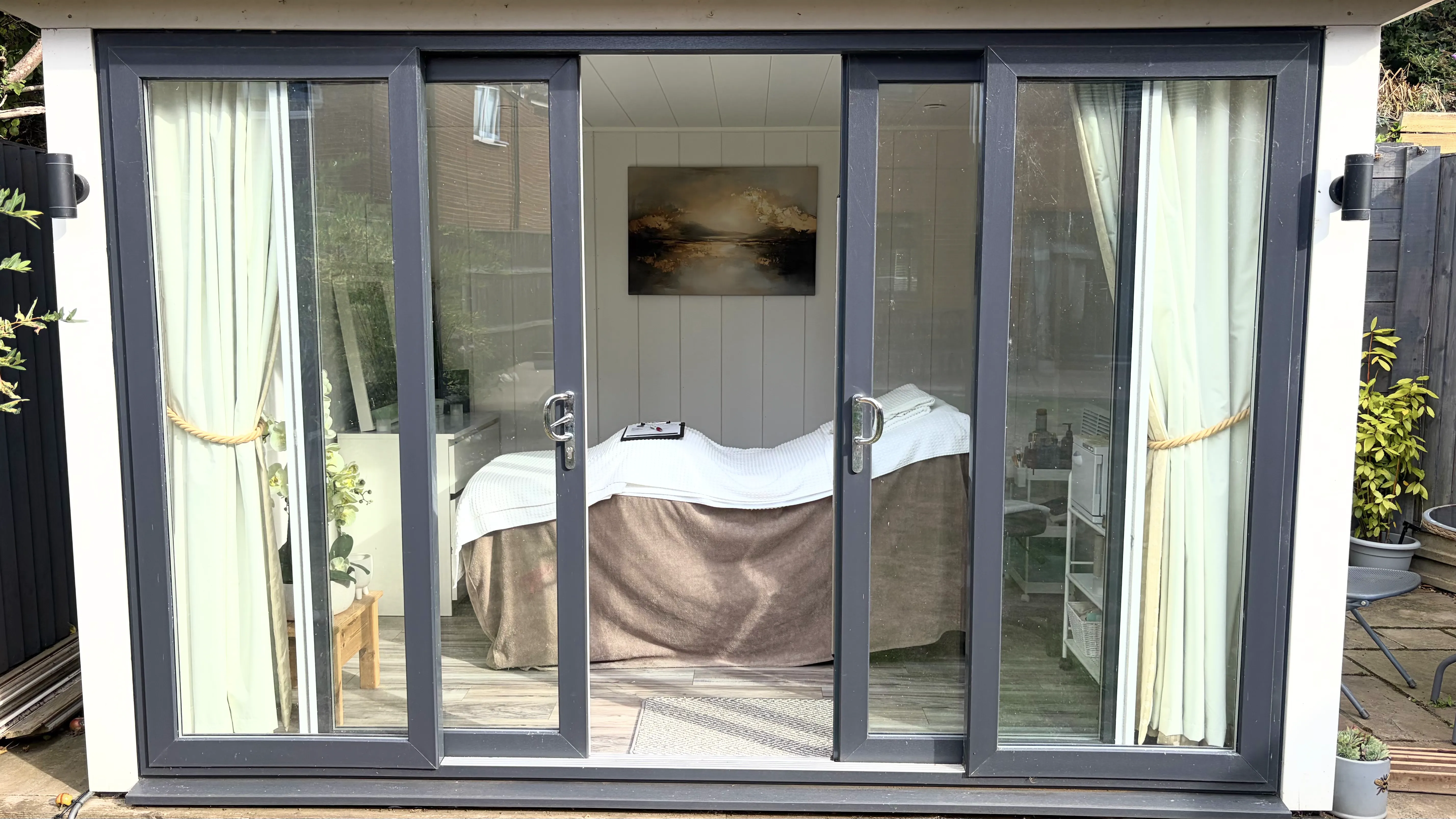 The garden room from the lawn, its sliding doors open onto the treatment room.